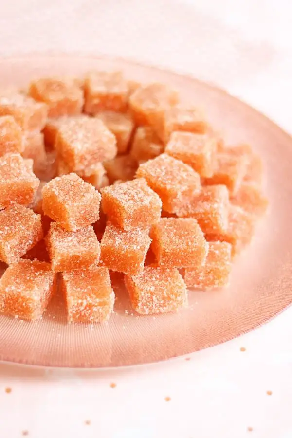 Pâte de coing saupoudrée de sucre cristallisé sur une assiette rose