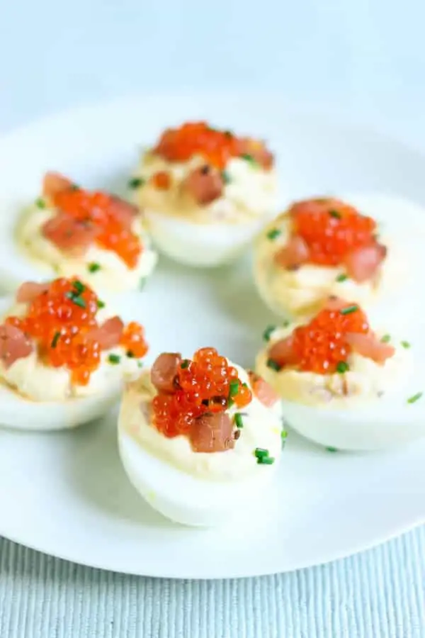Oeufs au saumon fumé sur assiette blanche garni de ciboulette et œufs de saumon