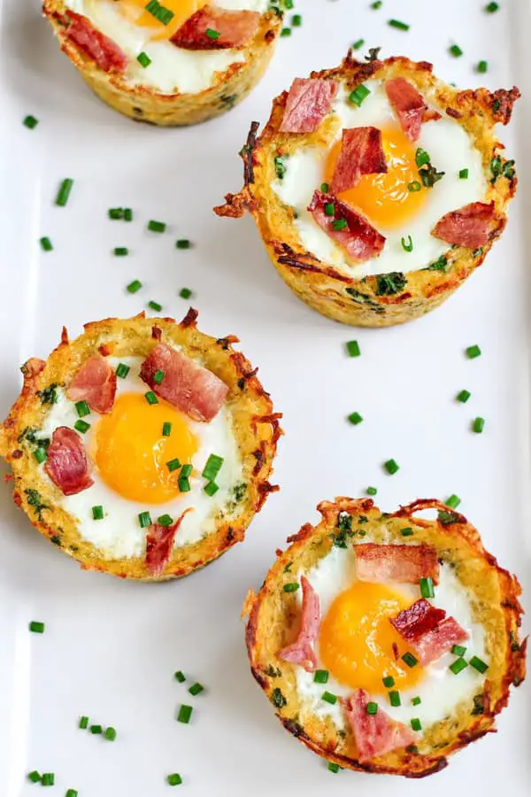 Nids de pommes de terre râpées garnis d’œufs, de bacon croustillant et de ciboulette.