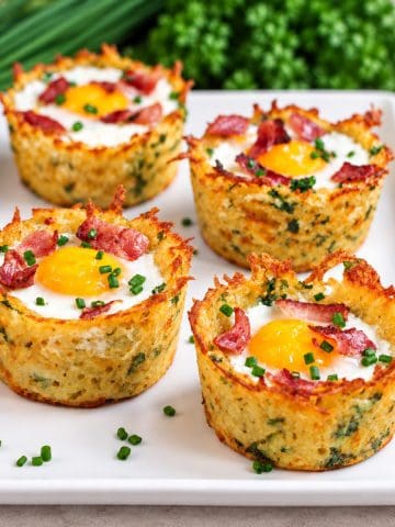 Nids de pommes de terre aux oeufs et bacon sur assiette blanche.