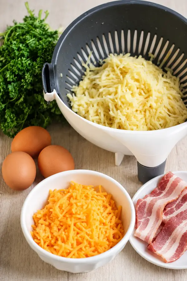 Ingrédients des nids de pommes de terre aux œufs et au bacon : pommes de terre râpées, œufs, fromage, bacon et persil frais.