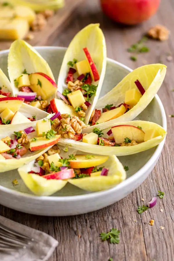 Salade d'endives en forme de fleur sur assiette blanche.