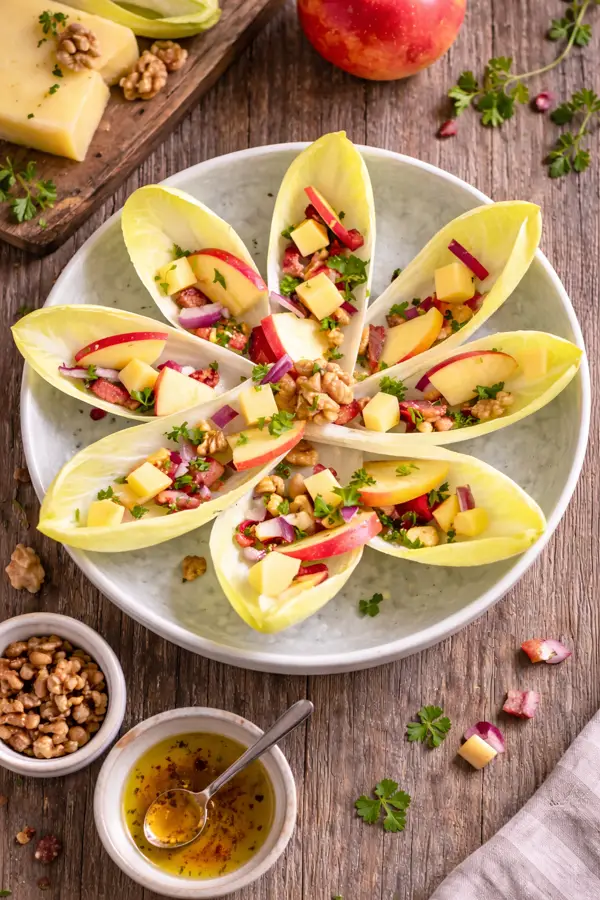 Salade d'endives en forme de fleur sur assiette blanche vue de haut.