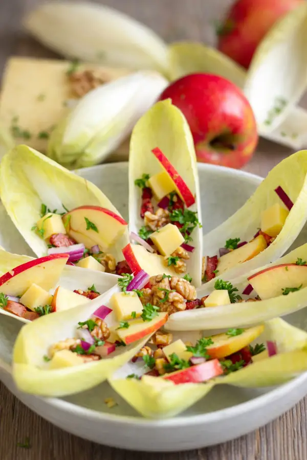 Salade d'endives en forme de fleur sur assiette blanche.