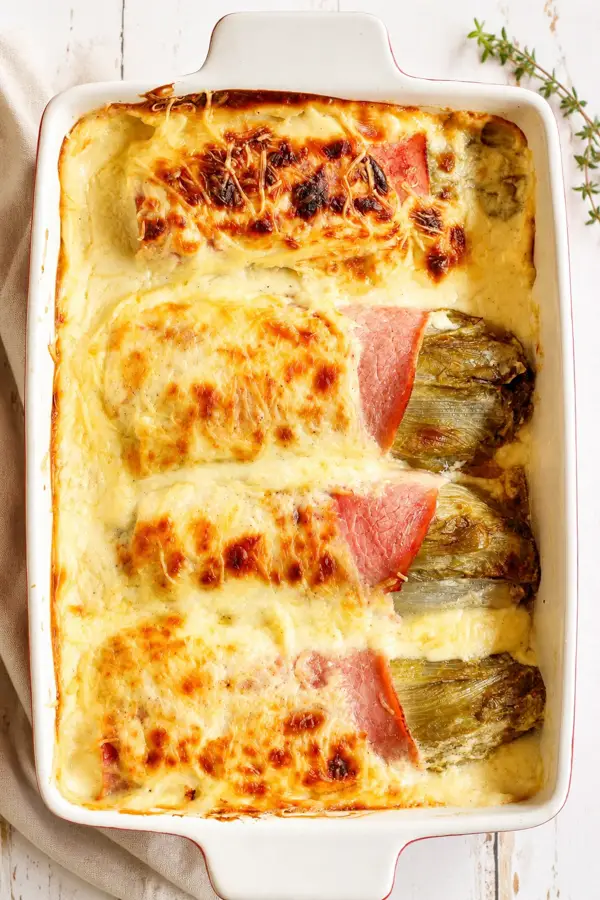 Endives au jambon et à la béchamel dans un plat a gratin.